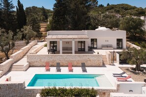 Uma villa moderna com piscina, degraus de pedra e espreguiçadeiras.