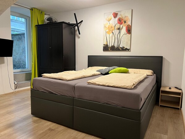 Une chambre moderne avec un lit, une armoire, un tableau et une fenêtre avec des rideaux.