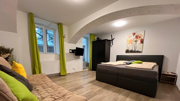 A modern bedroom with a large bed, a sofa, and a TV mounted on the wall. - Long Stay 1BR Apt Near Prater Park (Vienna)