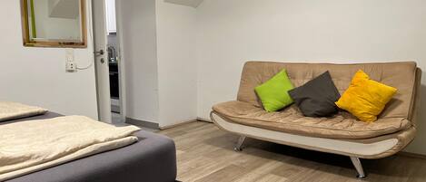 A modern room with a sofa, a bed, and a mirror.