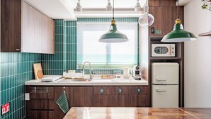 Una cocina con baldosas verde azulado, armarios de madera, un microondas y un refrigerador de estilo vintage.
