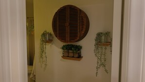 A hallway with a wooden wall decoration, a shelf with potted plants, and hanging plants. - Welcome to my Mushroom Cottage Enjoy this cozy & Unique  Home (Big Bear)