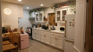 A kitchen with white cabinets, a pink refrigerator, and wooden chairs. - Welcome to my Mushroom Cottage Enjoy this cozy & Unique  Home (Big Bear)