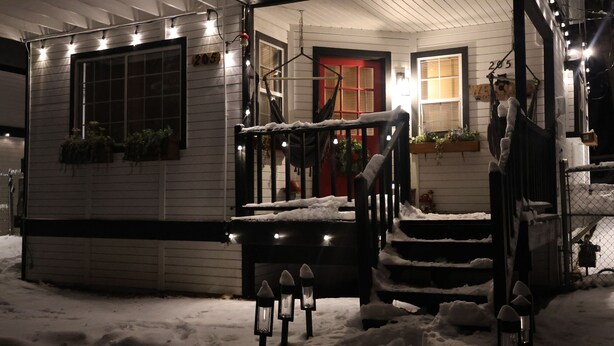 A snow-covered porch with a red door, outdoor lights, and potted plants. - Welcome to my Mushroom Cottage Enjoy this cozy & Unique  Home (Big Bear)