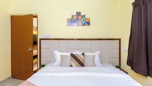 A hotel room with a bed, a painting on the wall, and a door. - City Haven by Jadecaps Nr. Belle Vue Hsp 3bhk (Kolkata)