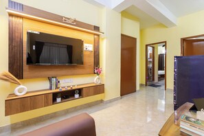 Una sala de estar moderna con un televisor de pantalla plana grande montado en una pared de madera, un sofá cómodo y una pequeña mesa de centro.