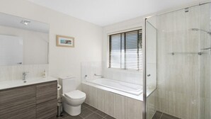 A modern bathroom with a toilet, sink, and bathtub. - Beautiful House with Mountain and Water Views and Kangaroos. (Long Beach)