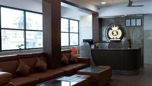 A modern lobby with leather sofas, a reception desk, and a ceiling fan. - Skyline Residency (Bengaluru)