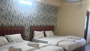 A hotel room with two beds, each with white linens and towels, a wooden headboard, and a wall with a forest pattern. - Skyline Residency (Bengaluru)