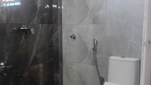A bathroom with a shower, toilet, and a blue water dispenser. - Skyline Residency (Bengaluru)