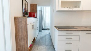 A narrow kitchen with white cabinets, a wooden cabinet, a red appliance, and a view into a hallway. - 15 Min to Vienna Center - Affordable & Simple 5BR Apt with WIFI (Vienna)