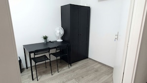 A small room with a desk, two chairs, a fan, a cabinet, and a potted plant. - 15 Min to Vienna Center - Affordable & Simple 5BR Apt with WIFI (Vienna)