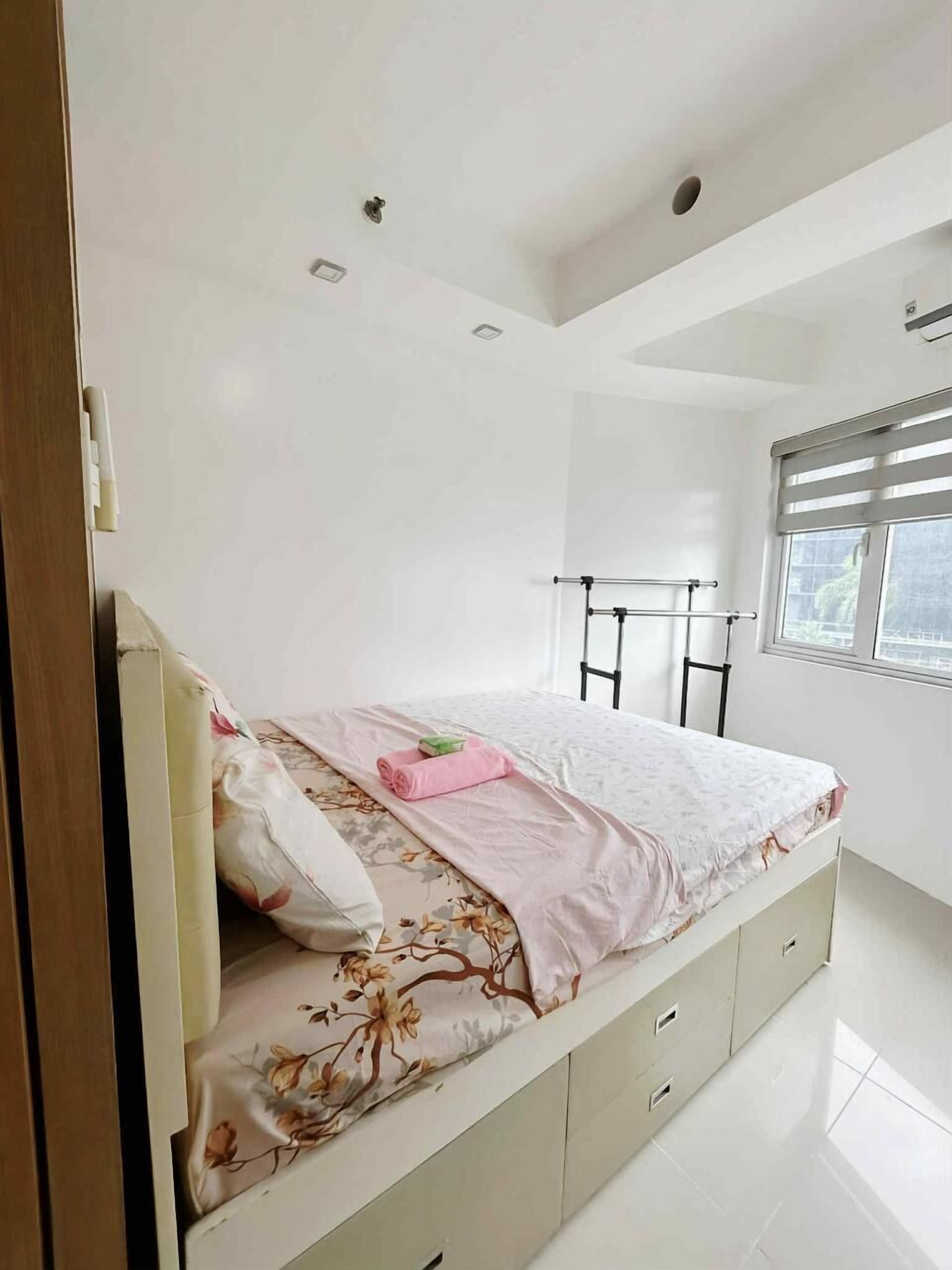 A bedroom with a bed, a window, and a ceiling light.