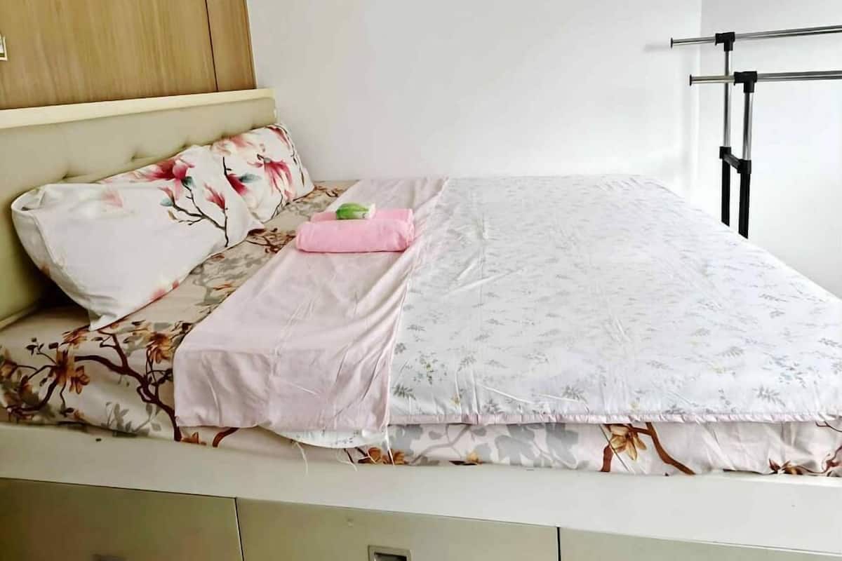 Une chambre à coucher comprenant un lit, une tête de lit en bois, une table de chevet et une armoire.