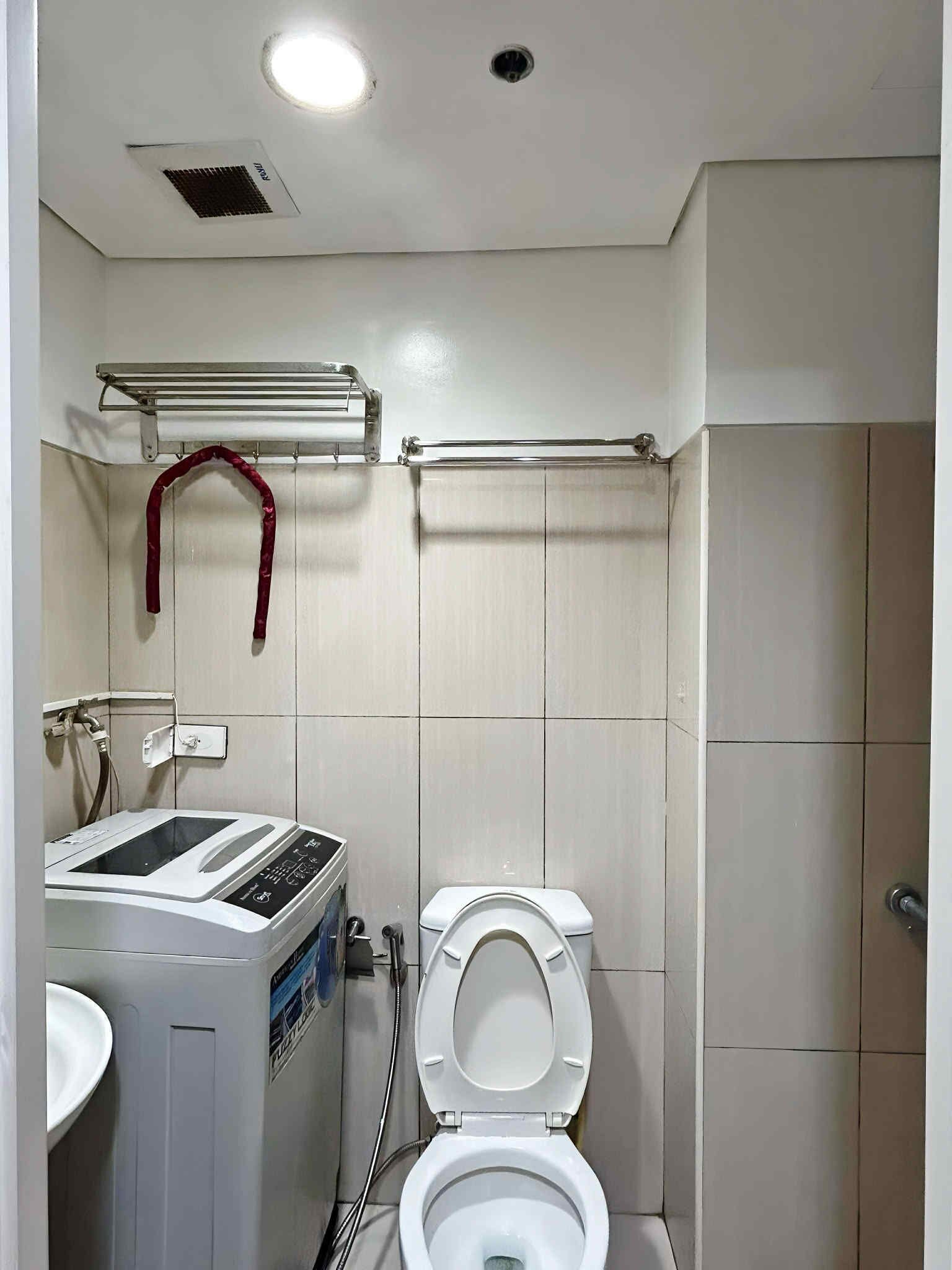 Un baño pequeño con lavadora, inodoro y zona de ducha.