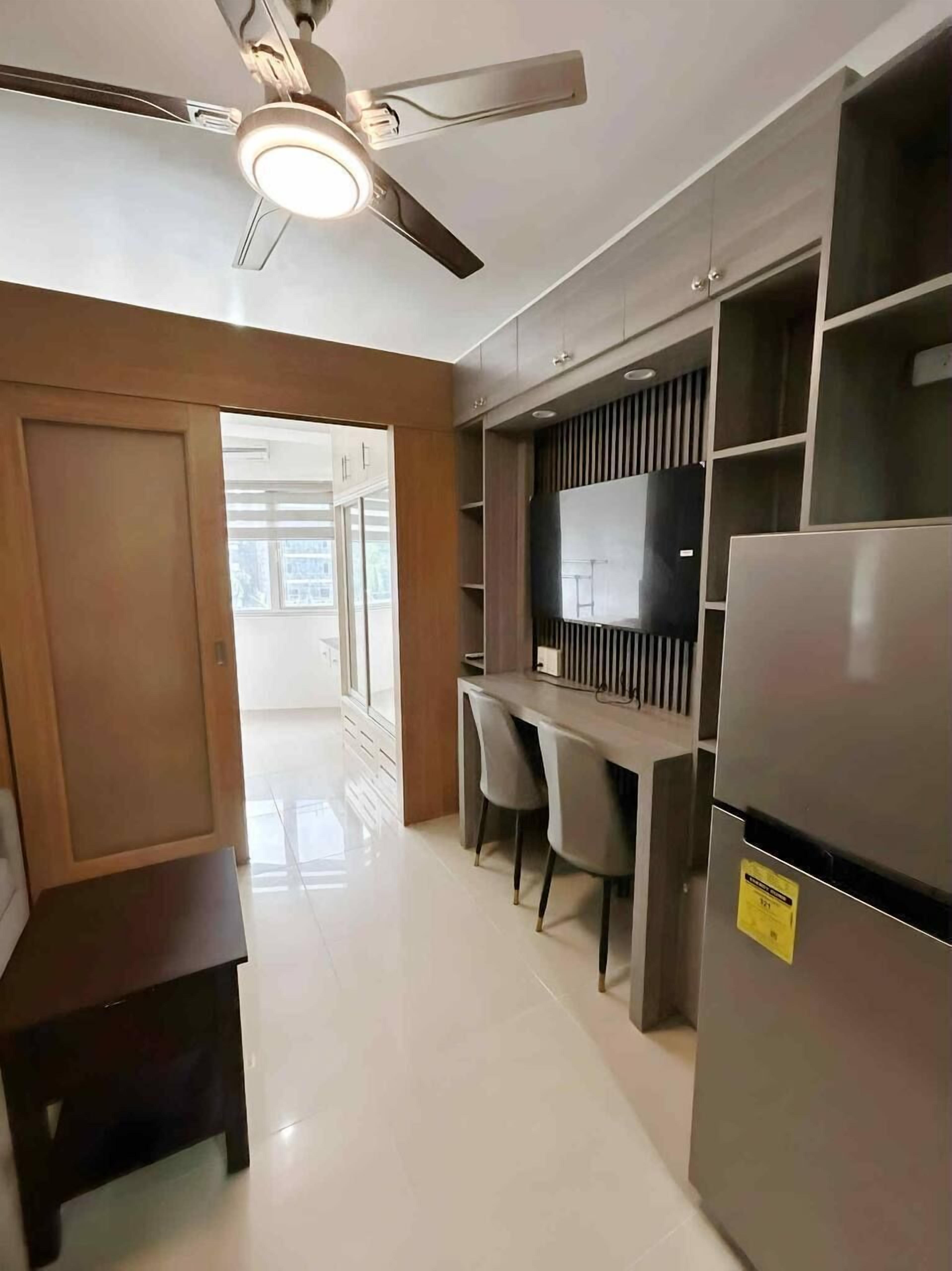 A modern kitchen with a built-in refrigerator, a dining area with chairs, and a ceiling fan.