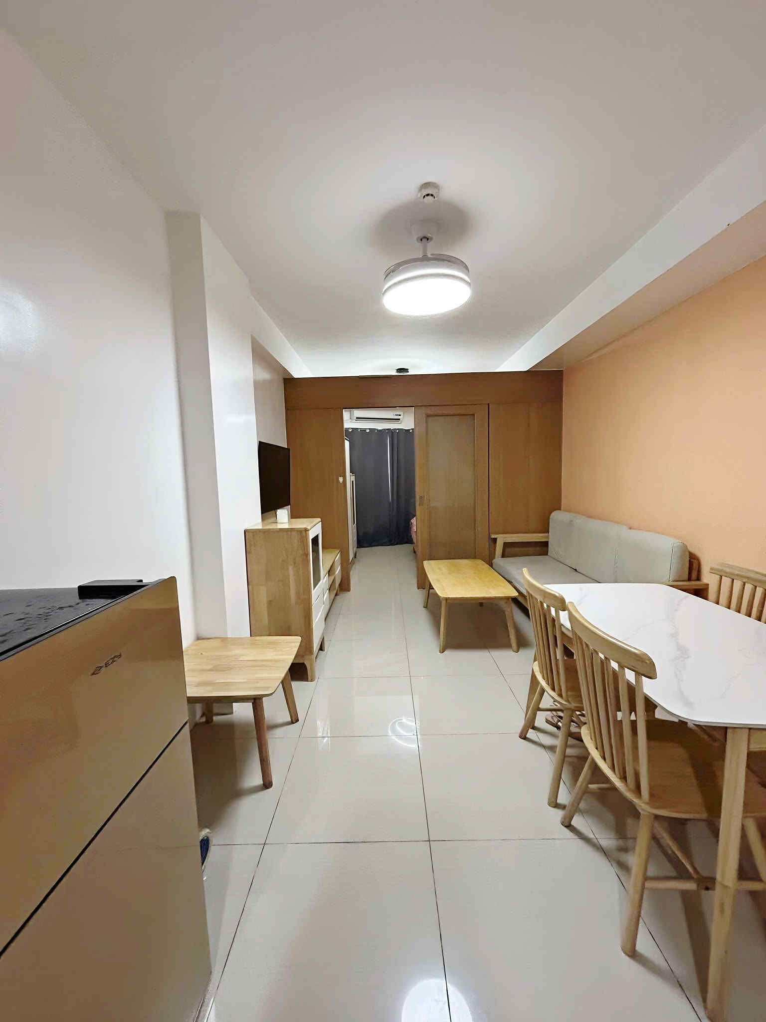 A modern kitchen with wooden cabinets, a built-in stove, and a dining area with wooden chairs and a table.