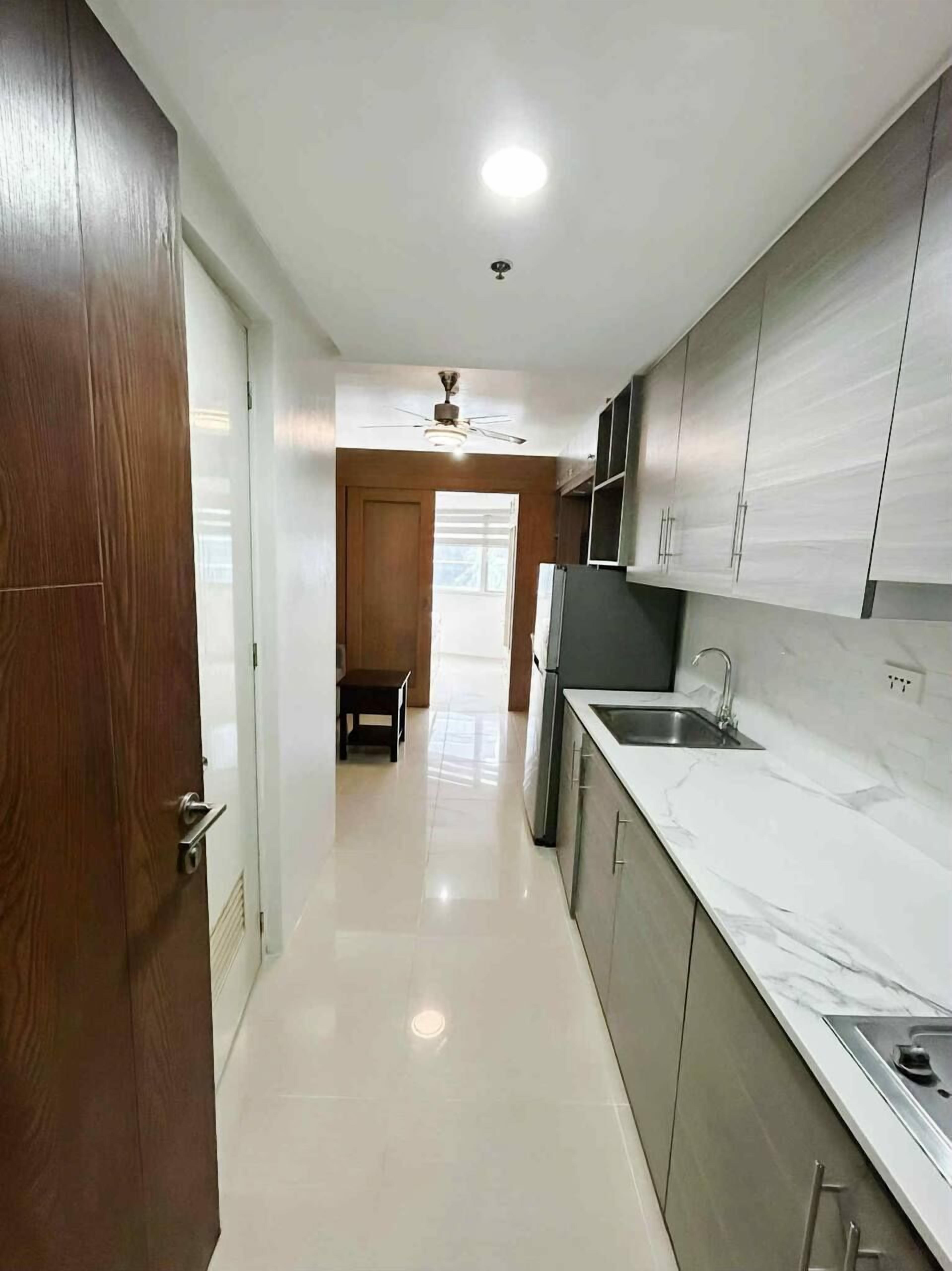 A modern kitchen with white marble countertops, stainless steel appliances, and wooden cabinets.