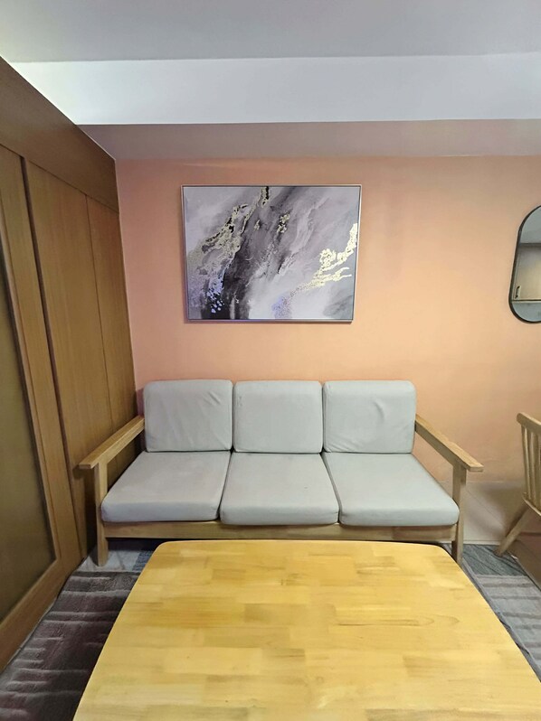 Une pièce avec un plancher en bois, un canapé, un tableau et un miroir.