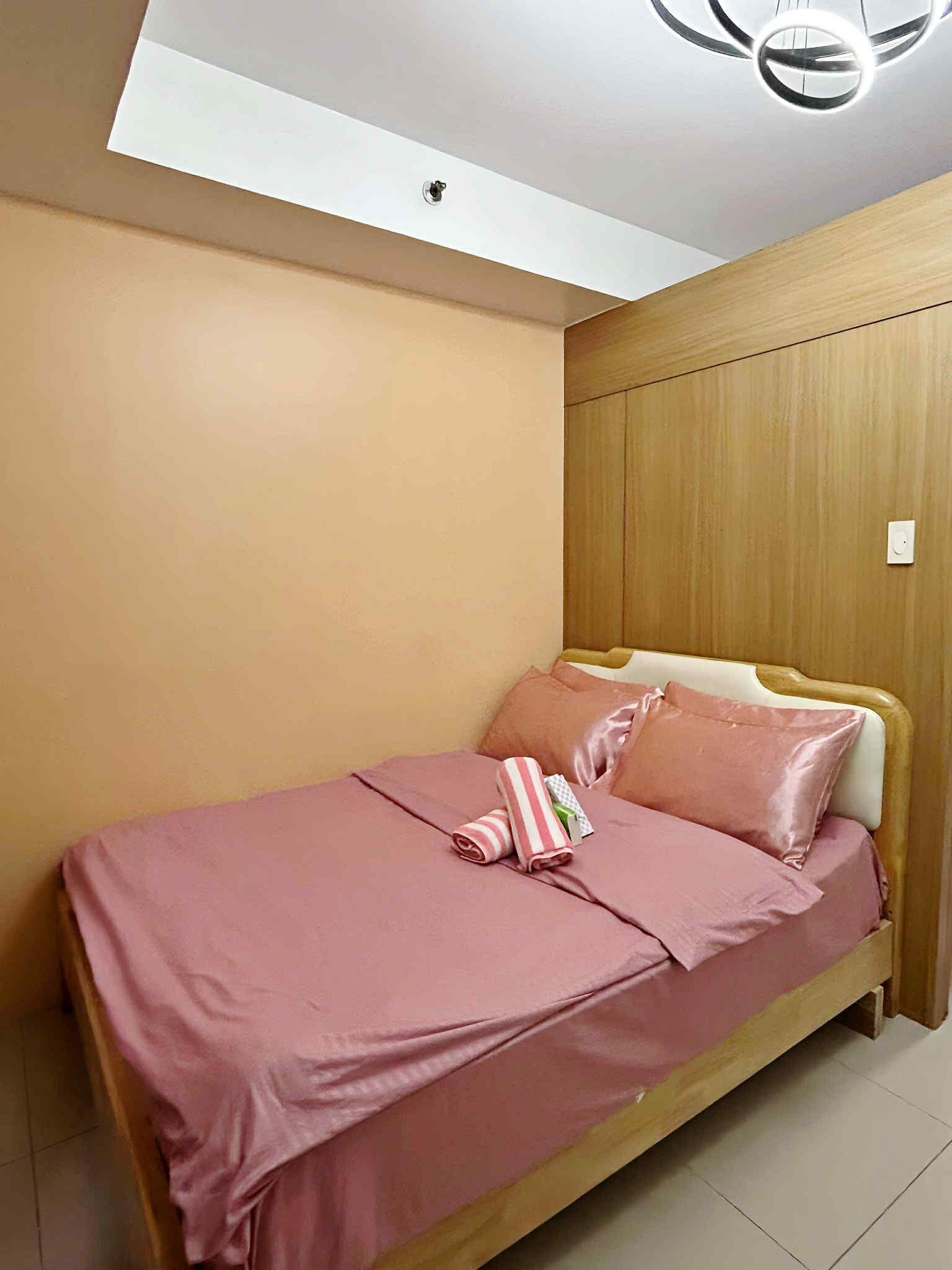 A bedroom with a bed, wooden paneling, and a ceiling light fixture.