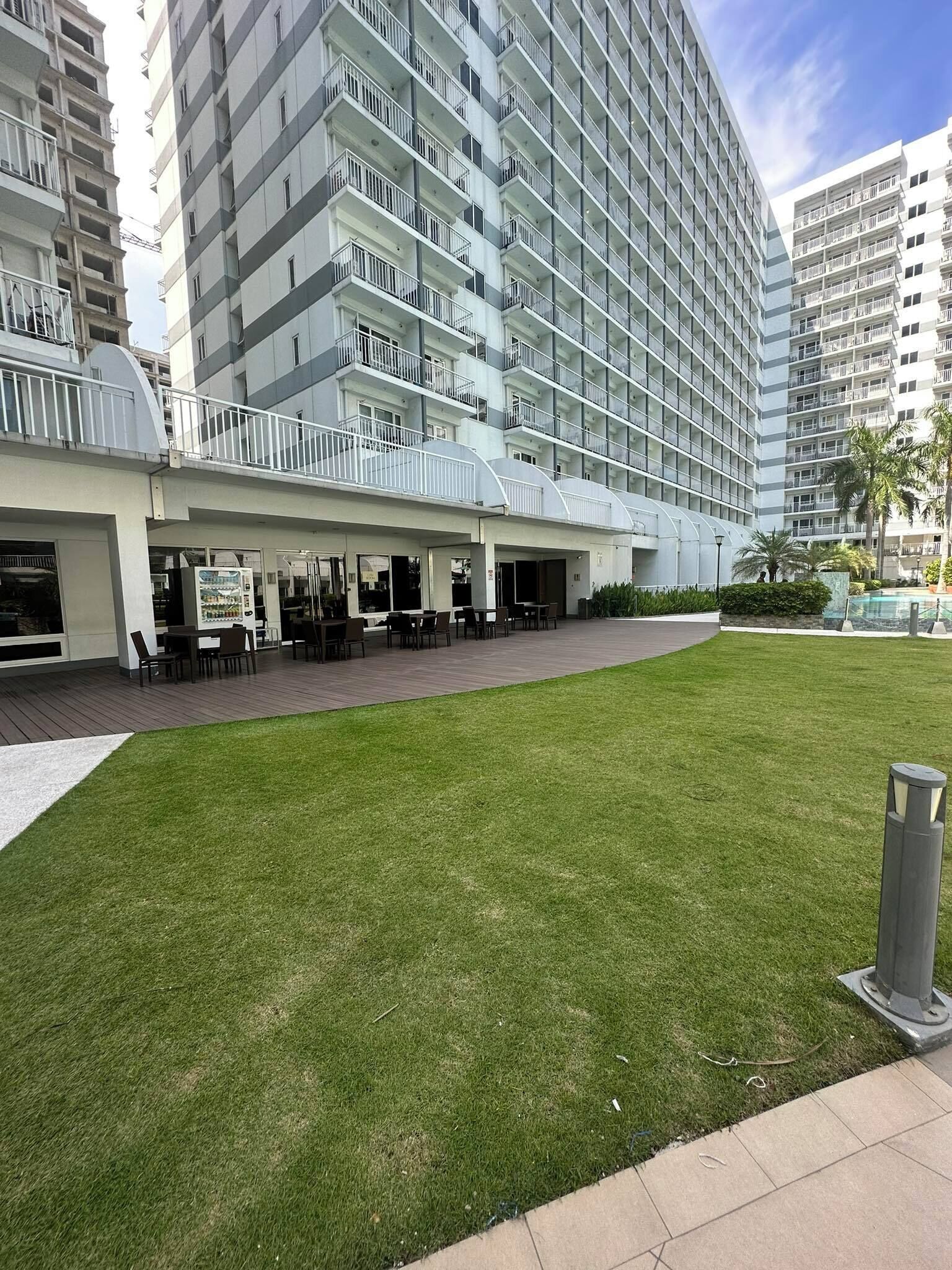 A modern hotel with a spacious outdoor seating area, a well-maintained lawn, and a pool.