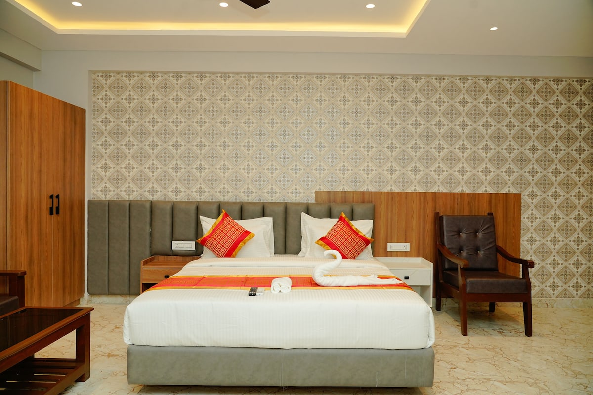 Quarto de hotel com uma cama grande, cabeceira de madeira e papel de parede estampado.