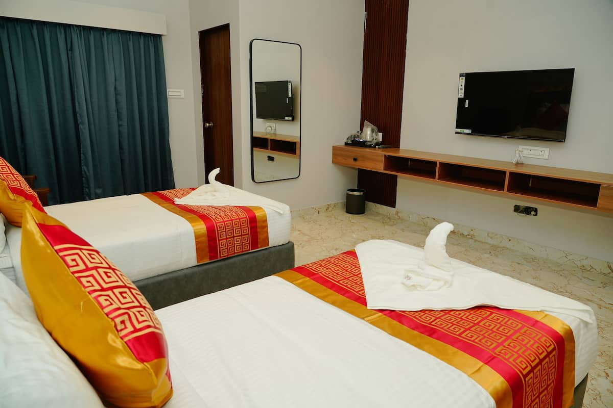 Quarto de hotel com duas camas, uma televisão, um espelho e uma prateleira de madeira.