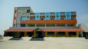 Un edificio de varios pisos con una entrada destacada, techo plano y una serie de ventanas.