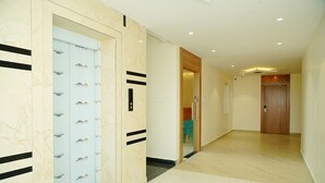 Un pasillo con suelo de mármol, puerta de madera y pared con diseño de rayas negras.