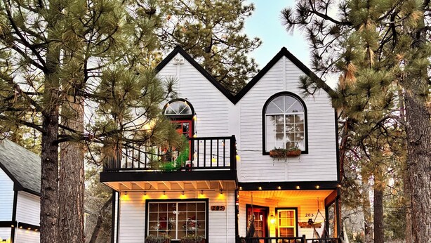 A white two-story house with a balcony, a small porch, and a garage. - Welcome to my My Cozy Mushroom cottage ! (Big Bear)