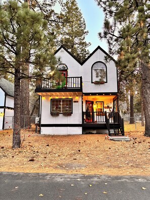 A white two-story house with a balcony, a small porch, and a garage. - Welcome to my My Cozy Mushroom cottage ! (Big Bear)