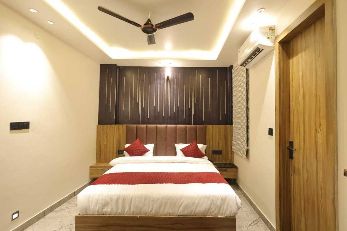 A modern bedroom with a bed, wooden headboard, ceiling fan, and recessed lighting.