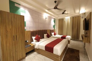 A hotel room with two beds, wooden wardrobe, ceiling fan, and a TV mounted on the wall. - Hotel Aurum Stay (Haridwar)