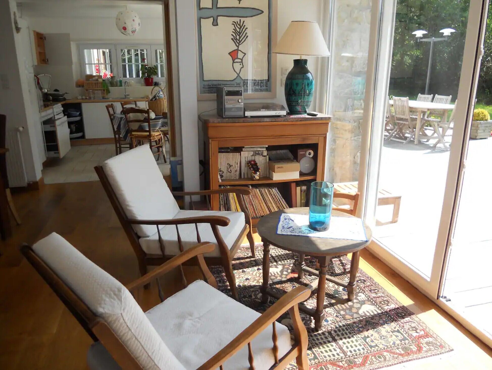 Un salon confortable avec un canapé, des fauteuils, une table basse et une bibliothèque. Une fenêtre offre une vue sur l’extérieur.