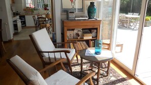 Un accogliente soggiorno con divano, poltrone, tavolino da caffè e libreria. Si vede una finestra con vista sull'esterno.