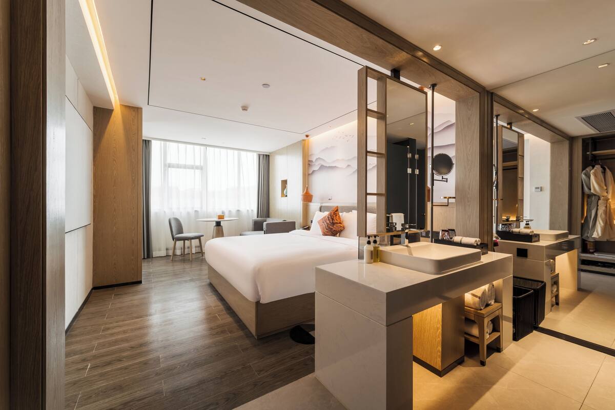 Een moderne hotelkamer met een groot bed, een apart badgedeelte en een bureau met stoel.