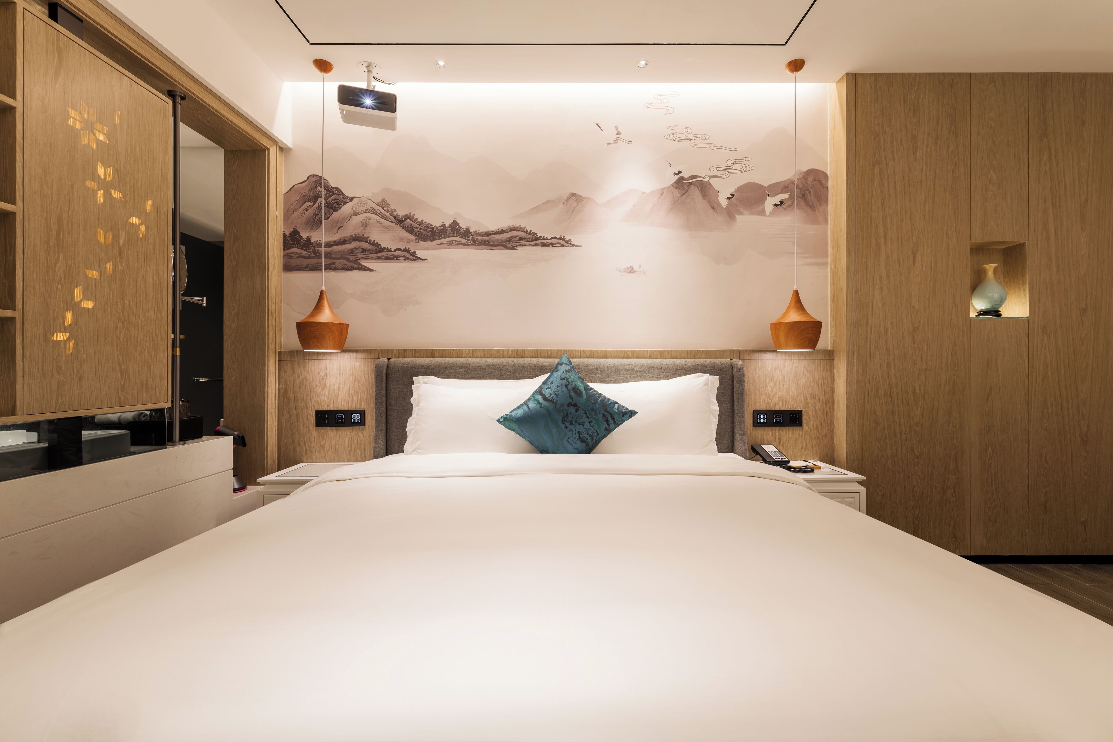 Et moderne hotelværelse med en stor seng, et træhovedgærde og et vægmaleri af bjerge og vand.