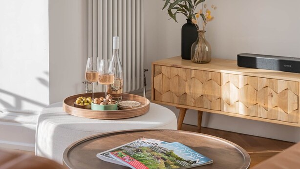 A living room with a round coffee table, a magazine, a wooden cabinet, and a vase with flowers. - Loughrigg at Lipwood House (Windermere)