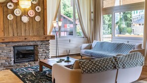 A cozy living room with a fireplace, a sofa, and a dining table. - Spacious 4BDR/9P apt at the foot of the ski slopes (Megève)