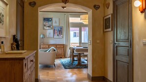 A hallway with a wooden cabinet, a bathtub, and a dining table with chairs. - Spacious 4BDR/9P apt at the foot of the ski slopes (Megève)