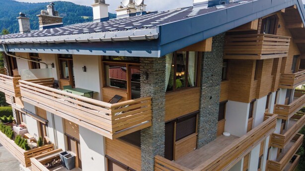 A multi-story building with balconies, stone facade, and a view of mountains. - Spacious 4BDR/9P apt at the foot of the ski slopes (Megève)
