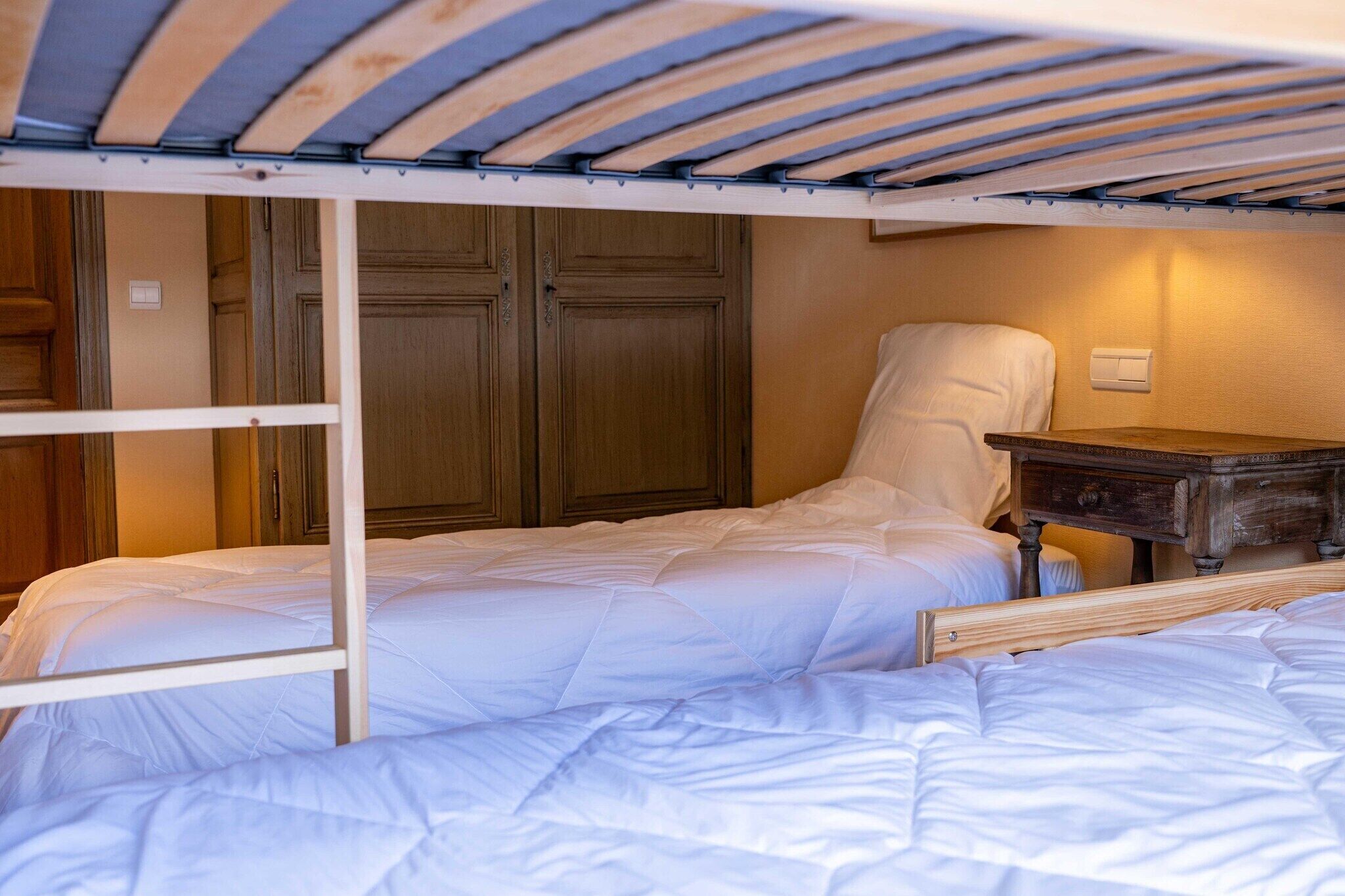 A bunk bed with a wooden ladder, a bedside table, and a wardrobe in a hotel room.