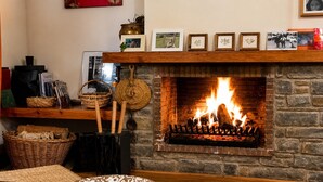 Une cheminée avec un feu, une cheminée en bois et des tableaux encadrés au-dessus.