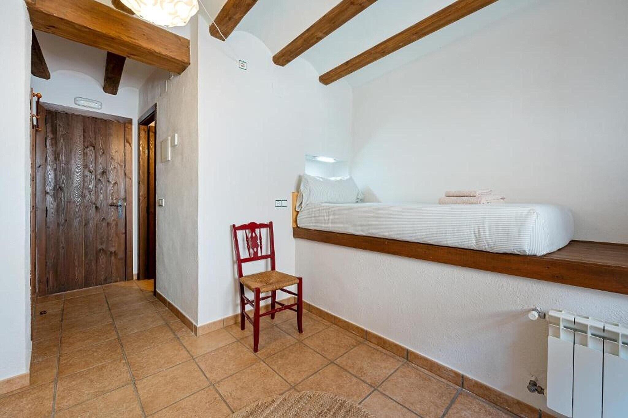 A bedroom with a bed, a wooden chair, a radiator, and a door.