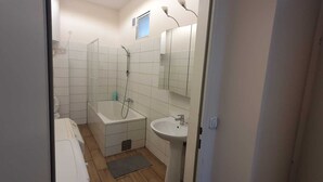 Ett litet, kompakt badrum med badkar, handfat och dusch.