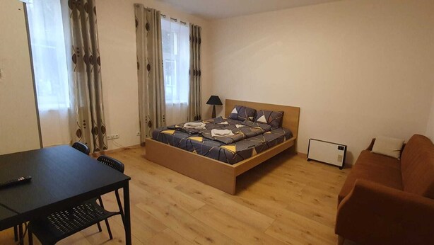 Ett litet sovrum med en säng, ett skrivbord, en stol, en värmare och en soffa.