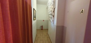 Un corridoio con un estintore, una porta contrassegnata con una 'A' e un muro decorato.