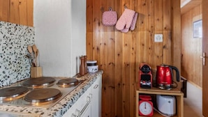 Una cocina con estufa, cafetera y balanza sobre una encimera de madera.