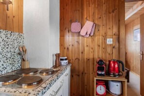 A kitchen with a stove, a coffee maker, and a scale on a wooden counter.