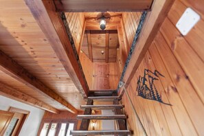 A wooden interior with a central staircase leading to a ceiling light fixture.